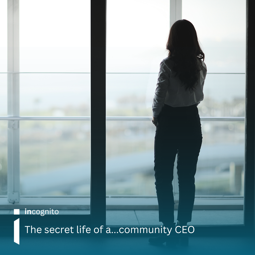 Image of a professional female, looking away from the camera, in a white shirt, black trousers and black boots, looking out of a large office window.