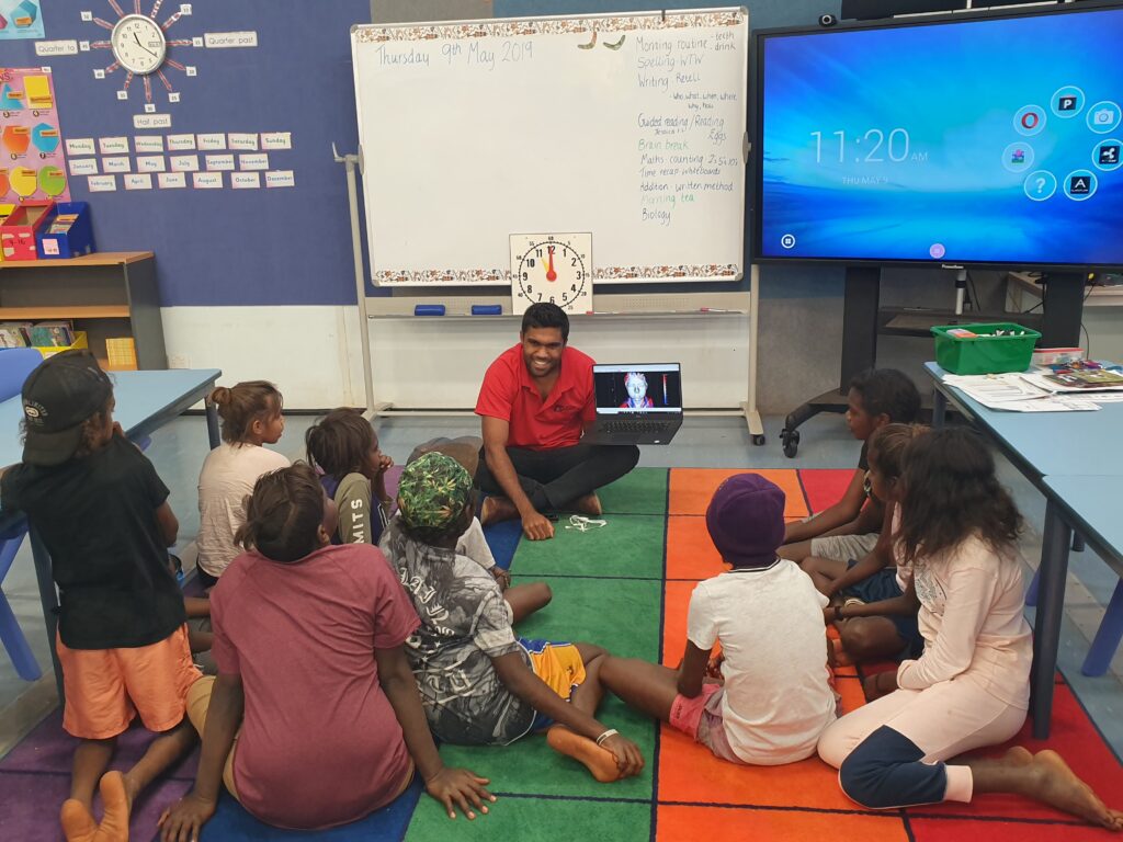 Photo of Yarluru Thomas engaging with children in a school setting