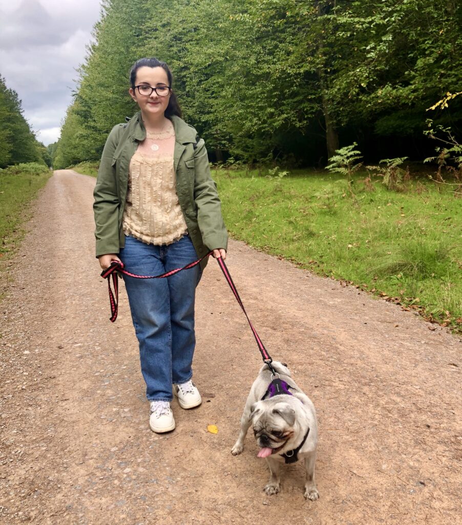 Tasmin walking her dog ( a pug) in the woods

Tasmin lives with various rare conditions—APDS2 (activated phosphoinositide 3-kinase δ syndrome), postural orthostatic tachycardia syndrome, mast cell activation syndrome, oral allergy syndrome, histamine intolerance, aquaporin-4 antibody and MCADD (medium-chain acyl-CoA dehydrogenase deficiency). 