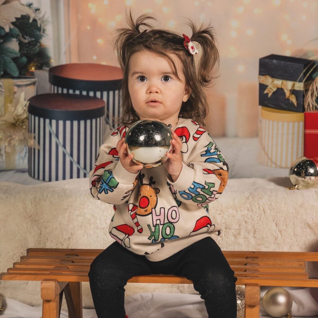 Mila wearing a Christmas jumper holding a silver bauble