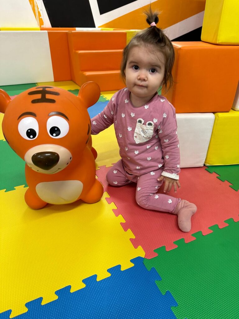 Mila with a tiger inflatable toy sitting in a soft play