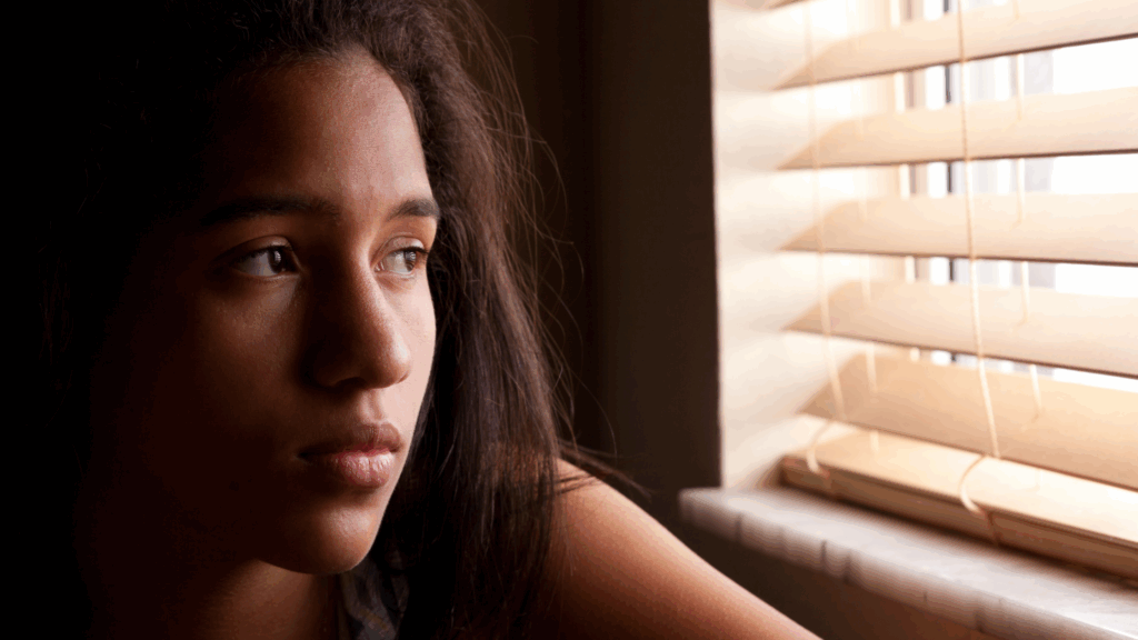 Image of a young woman staring thoughtfully out a window