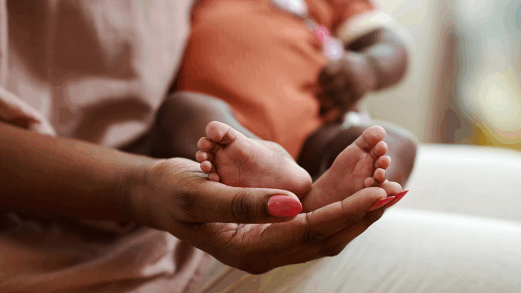 Image of a lady holding the feet of a newborn baby