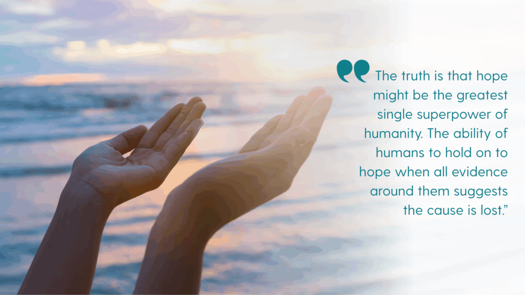 Image of hands reaching up palms, facing up, by the sea, to indicate hope