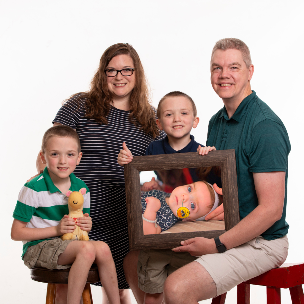 Photo of Lesa and her family: her husband, two sons and a photo of her daughter, Tori