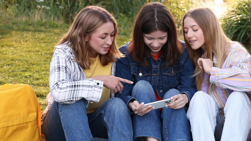 Photo of three teenage girls looking at a smart phone