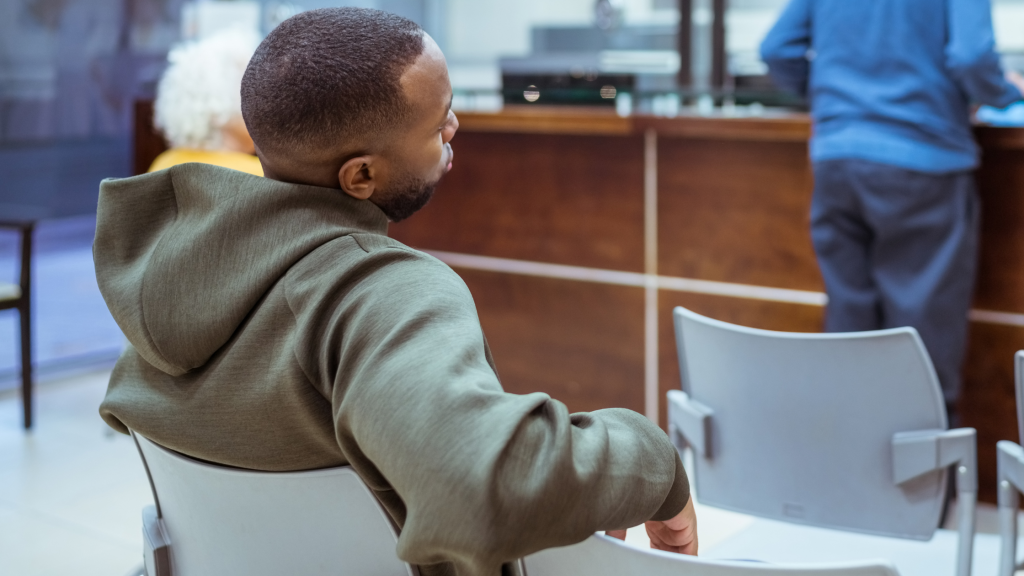 Photo of a frustrated man waiting in a doctor's waiting room to denote health inequalities, such as delayed diagnosis and lack of expert knowledge
