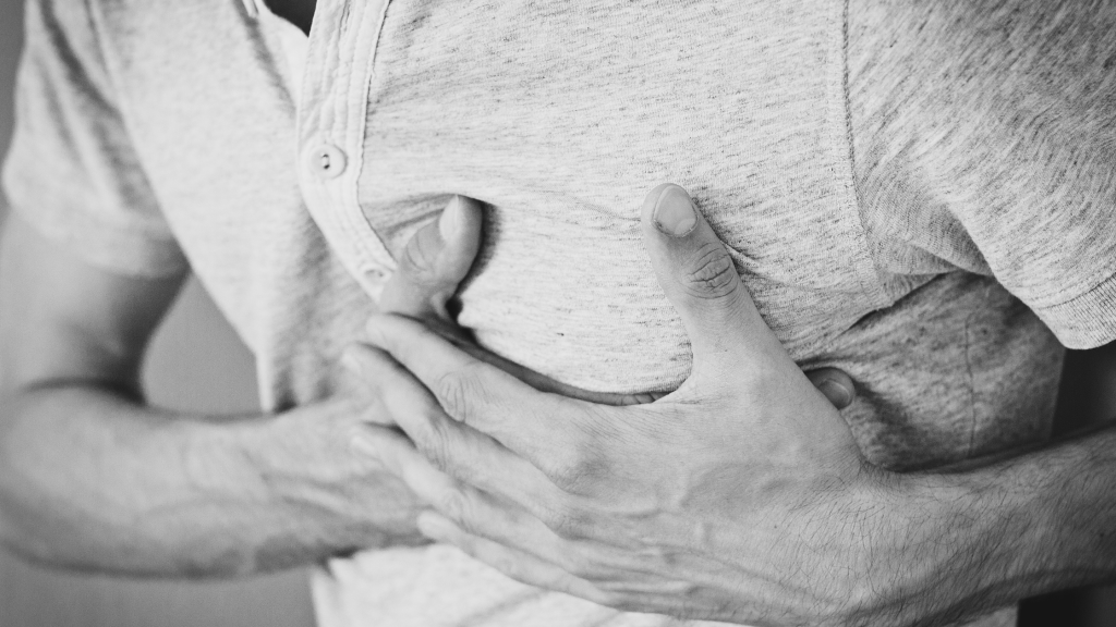 Photo of a man clutching his chest to denote heart disease