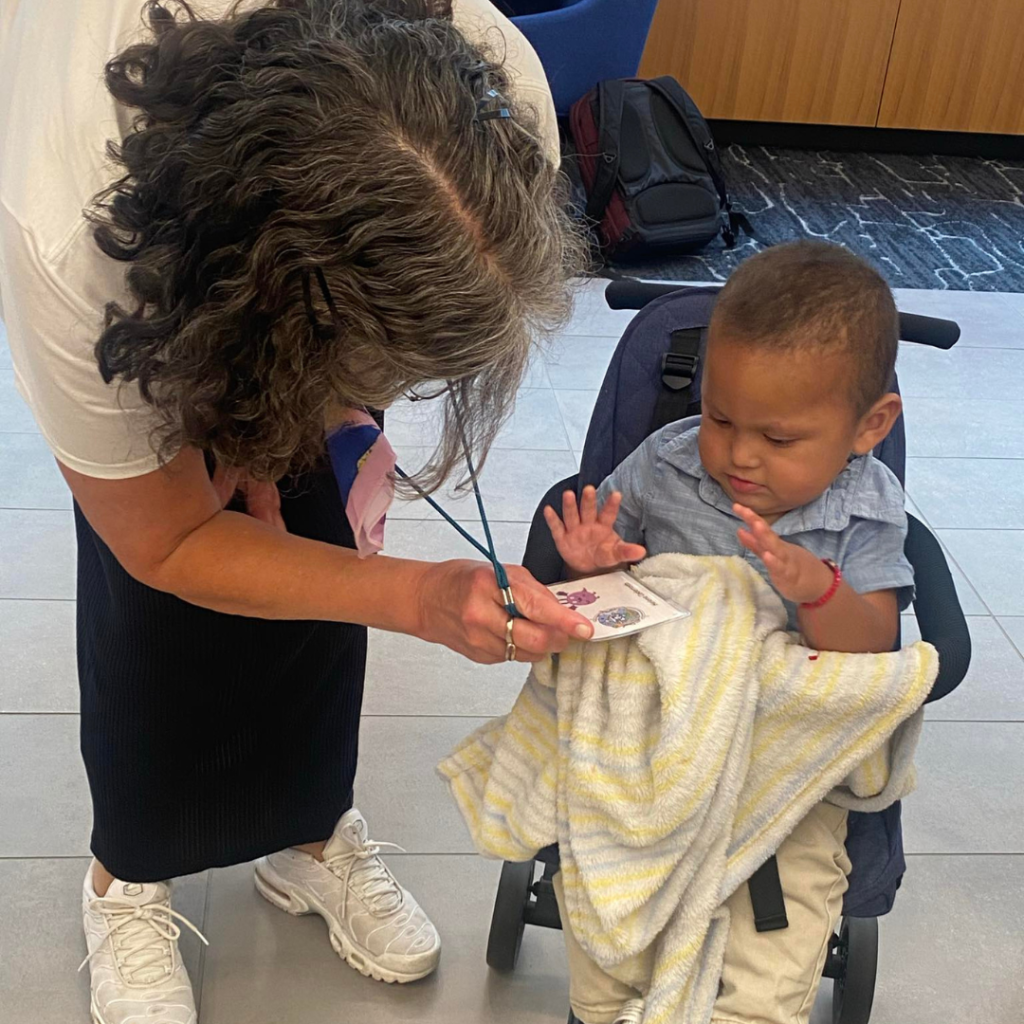 Image of a woman showing a baby in a push chair her lanyard