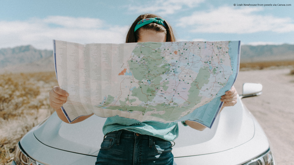 Photo of a young person looking at a map on a long road