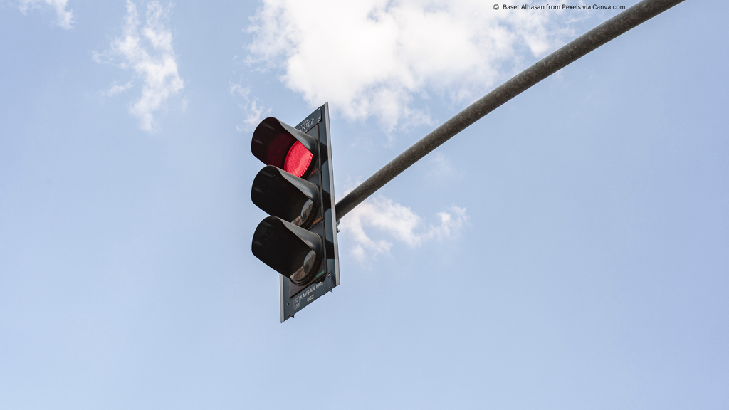 Image of red traffic light with blue sky background